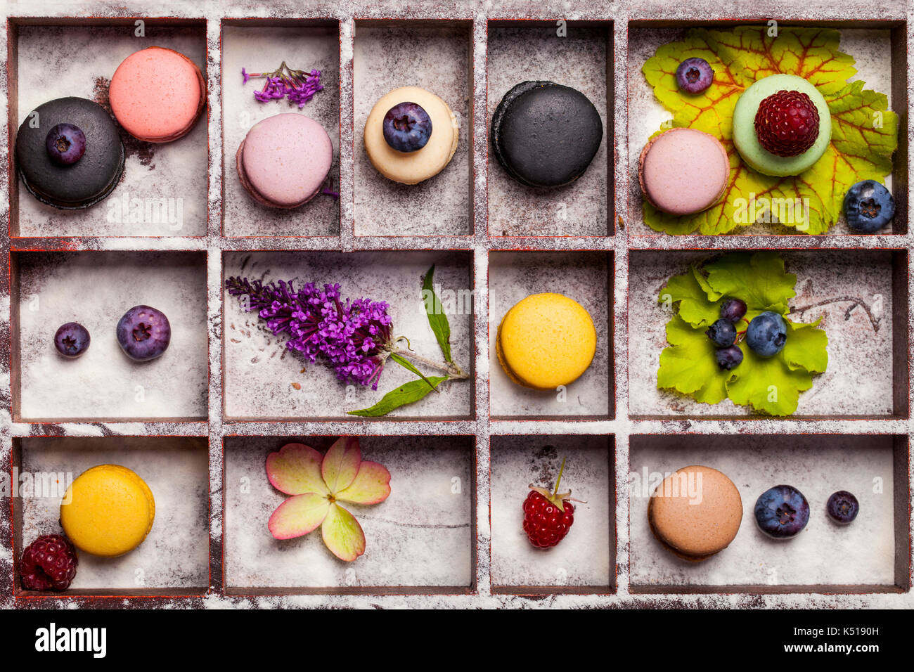 Varietà di coloratissimi dolce francese dessert - makaron ( les macarons) con fiori autunnali e bacche. Foto Stock