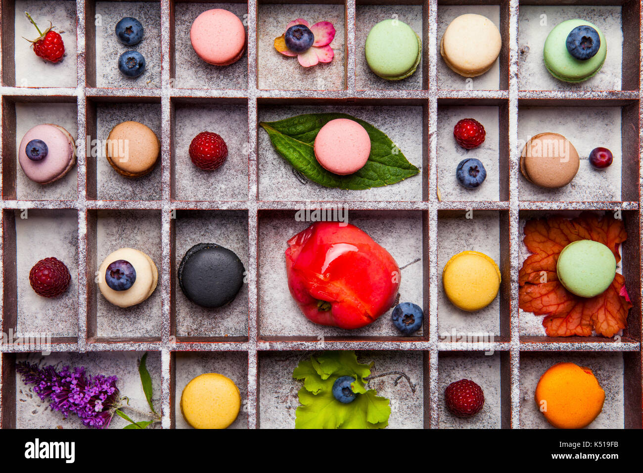 Varietà di coloratissimi dolce francese dessert - makaron ( les macarons) con fiori autunnali e bacche. Foto Stock