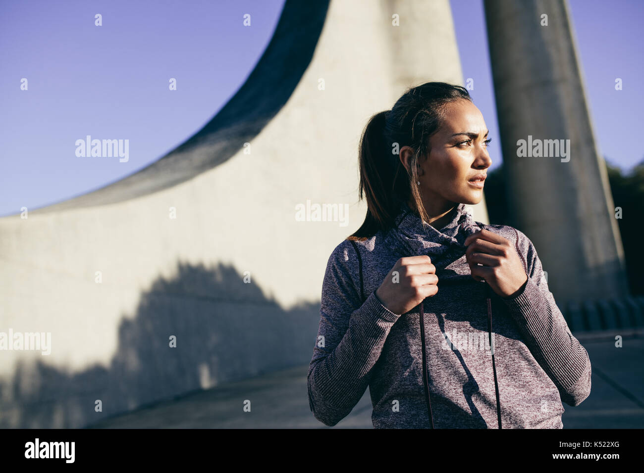 Un sano giovane donna in abbigliamento sportivo in piedi all'aperto al mattino e guardando lontano. Foto Stock