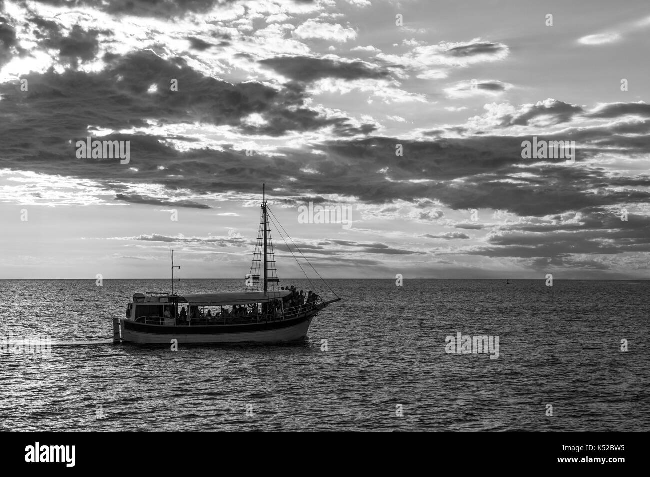 Una barca turistica sul mare al tramonto (dissaturato) Foto Stock