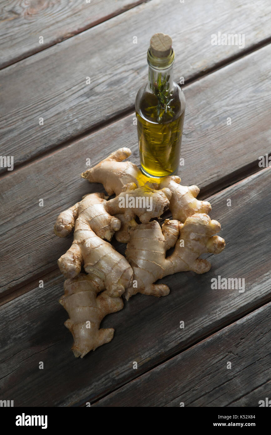 Angolo di alta vista di gingers dalla bottiglia di olio su tavola in legno Foto Stock