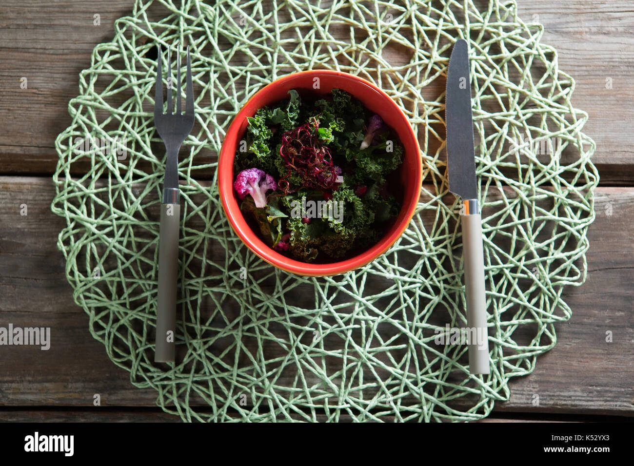 Vista aerea di insalata di verdure nella ciotola sul tappetino posto a tavola Foto Stock