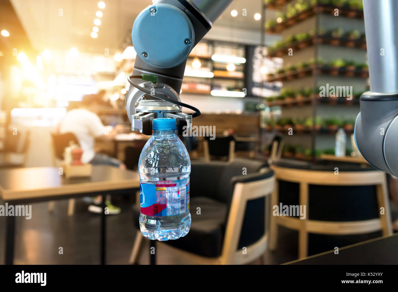 Robotics Tecnologia Tendenze concetto aziendale. Automazione del braccio di robot per servire bottiglia d'acqua in plastica nel ristorante con svasatura effetto di luce. Foto Stock