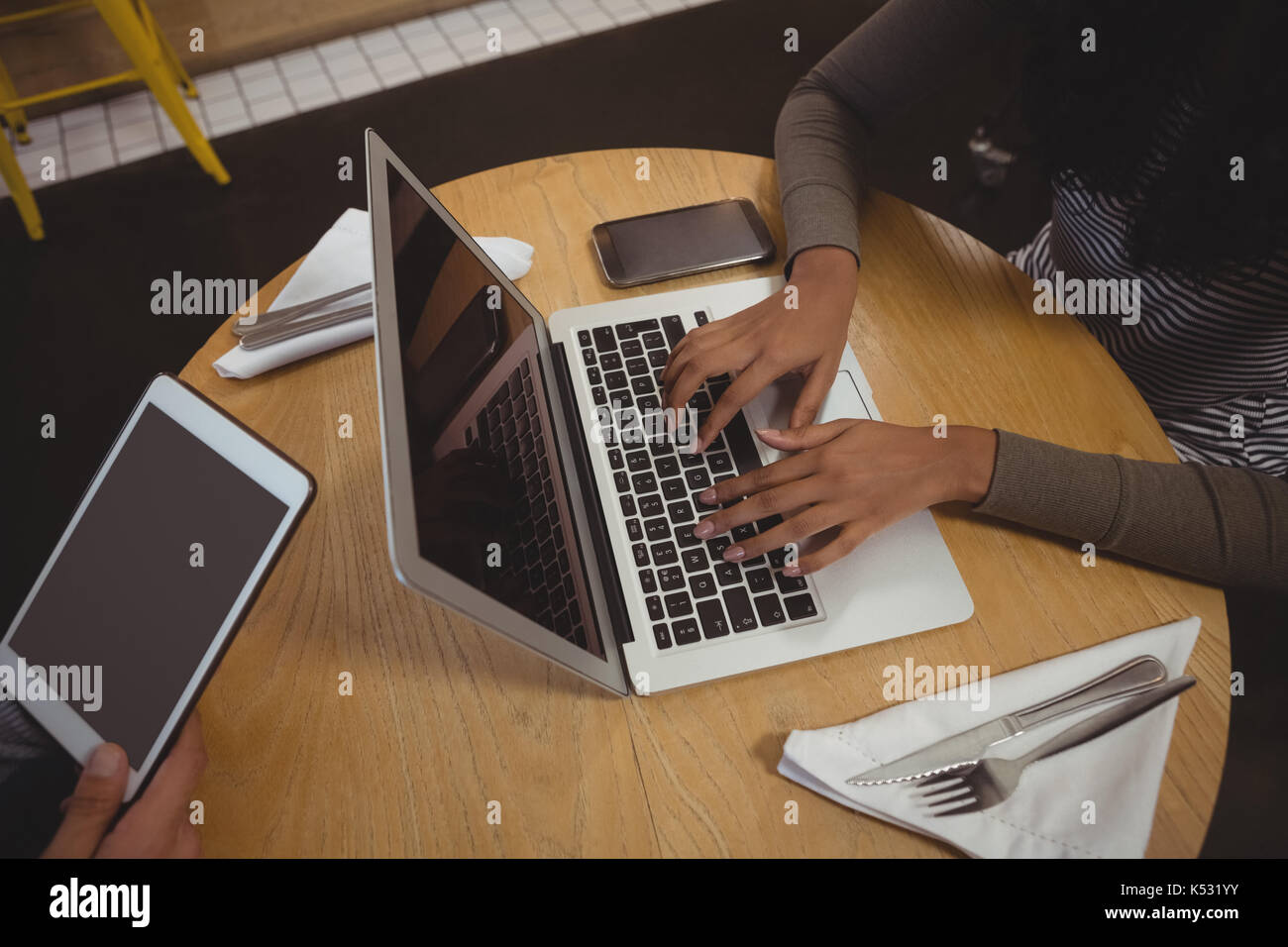 Immagine ritagliata della donna utilizzando il portatile in un tavolo di legno in cafe Foto Stock