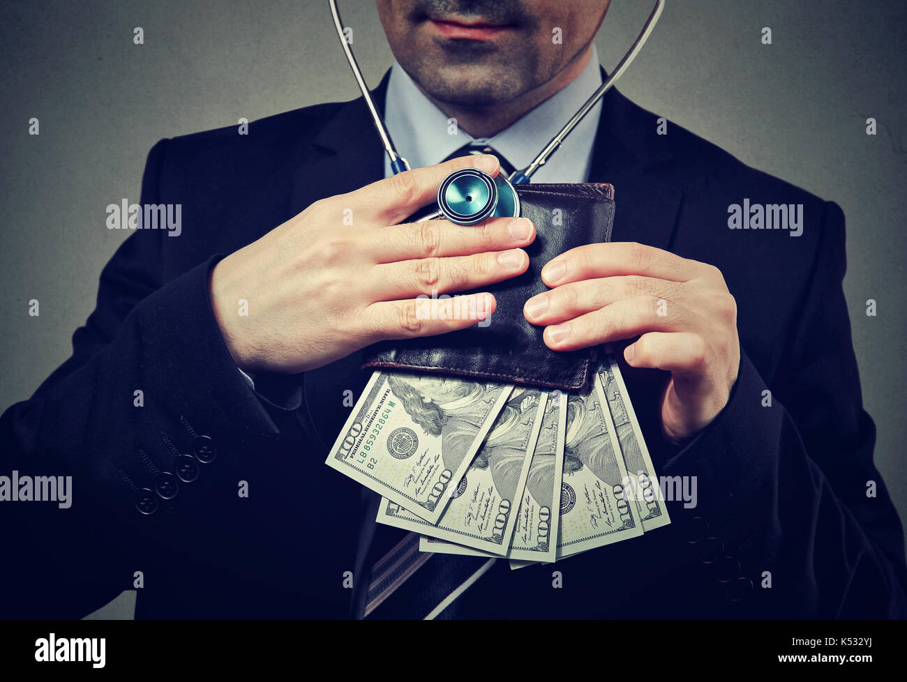 Imprenditore con stetoscopio in ascolto di portafoglio con banconote di dollari Foto Stock