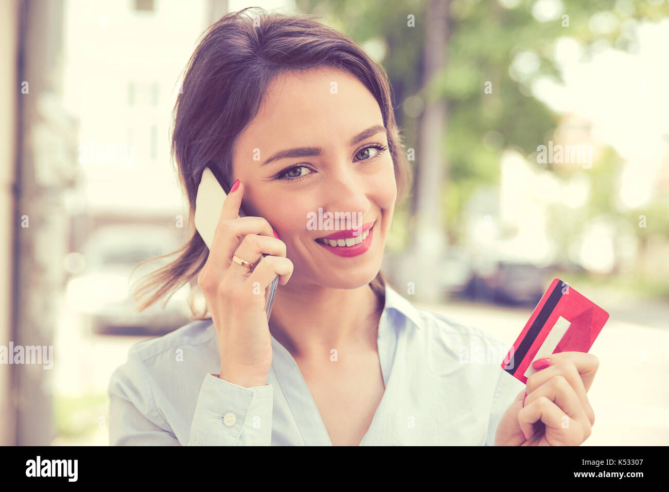 Ritratto di una donna felice di acquisto on-line facendo un oder con uno smart phone all'aperto Foto Stock