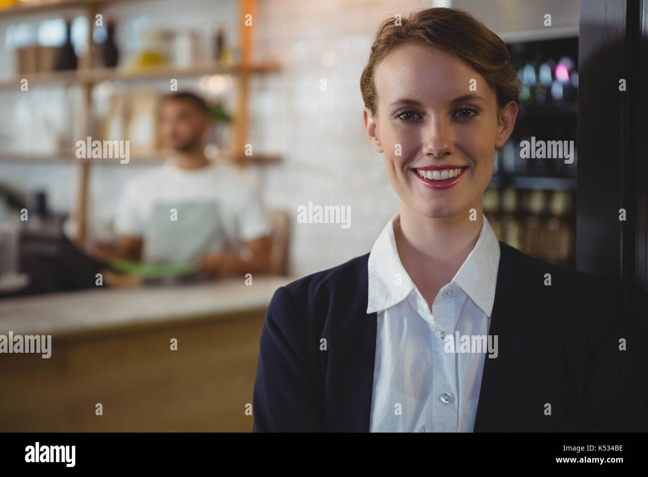 Ritratto di felice proprietario femmina con cameriere lavora in background al cafe Foto Stock