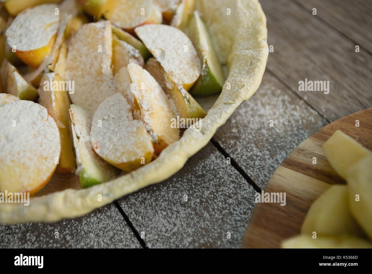 Angolo di alta vista di zucchero in polvere su fette di mela in teglia sul tavolo Foto Stock