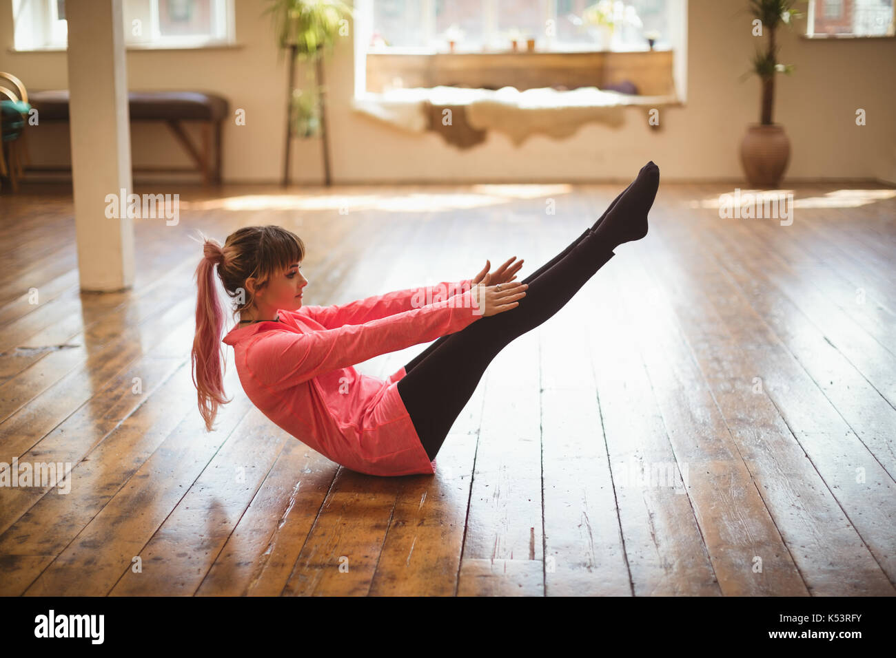 Vista laterale per tutta la lunghezza della donna fare yoga sul pavimento in legno Foto Stock