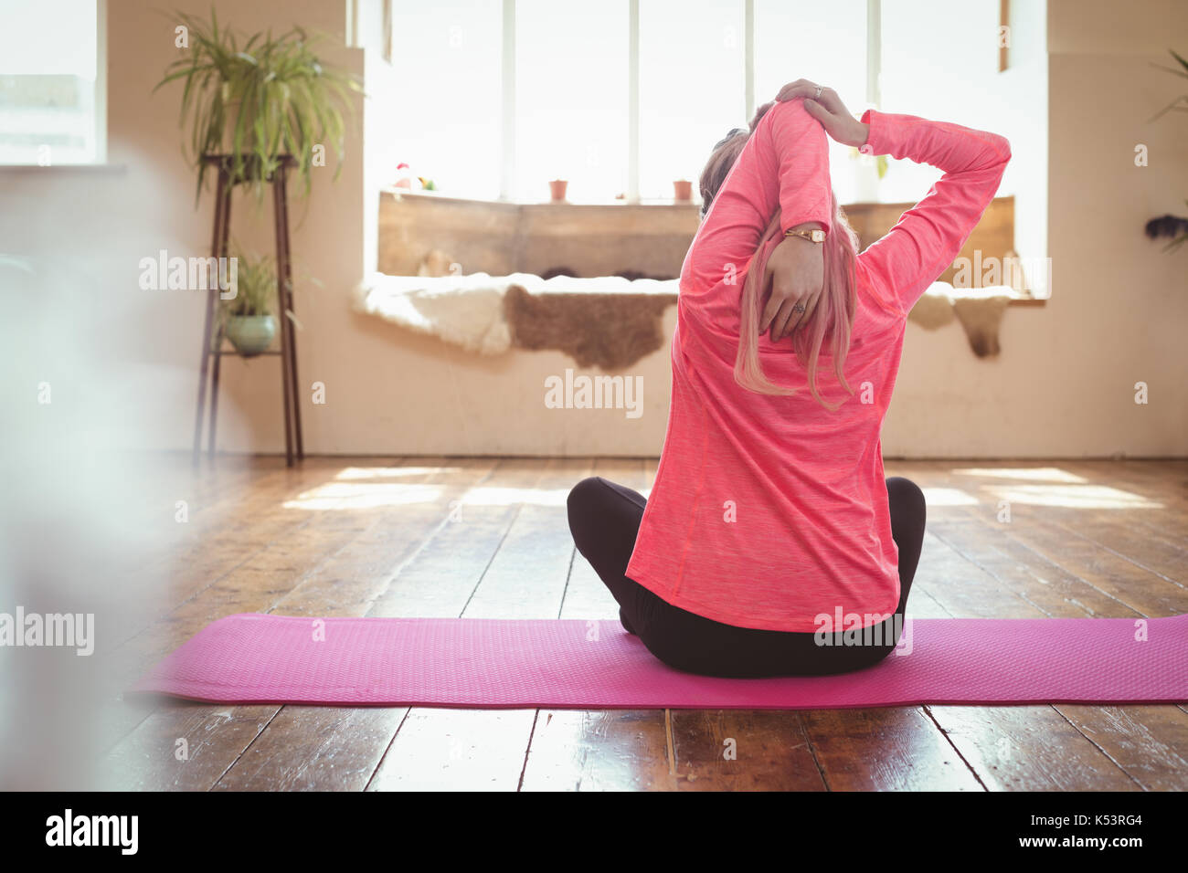 Vista posteriore del giovane donna facendo yoga a esercitare il tappetino in studio Foto Stock