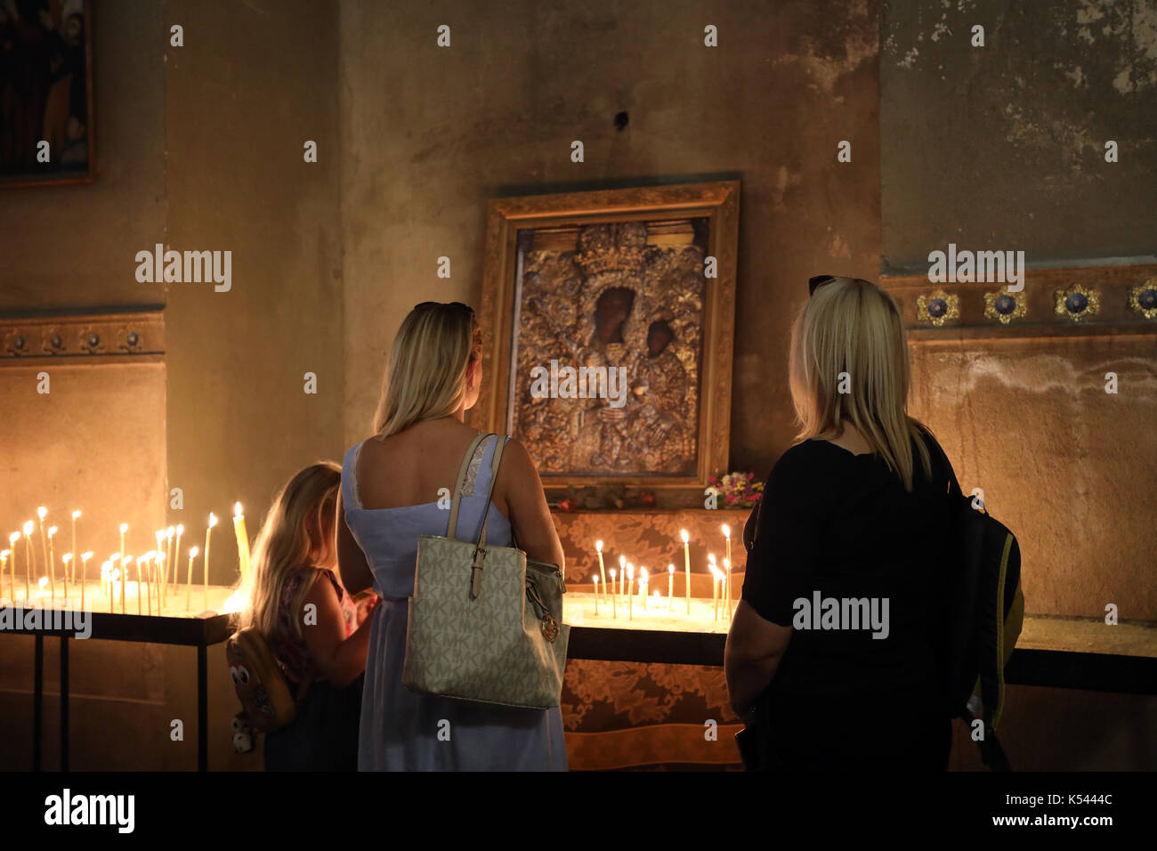 Adoratori pausa di contemplazione ad una icona della Madonna col Bambino, all'interno della Cattedrale armena nel centro di Lviv, Ucraina, il 27 agosto 2017. Th Foto Stock