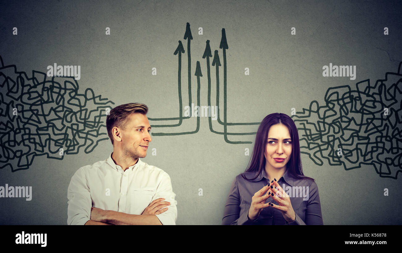 Profilo laterale di un giovane uomo e donna che guarda ad ogni altro ottenere i loro pensieri insieme isolato sul muro grigio sfondo Foto Stock
