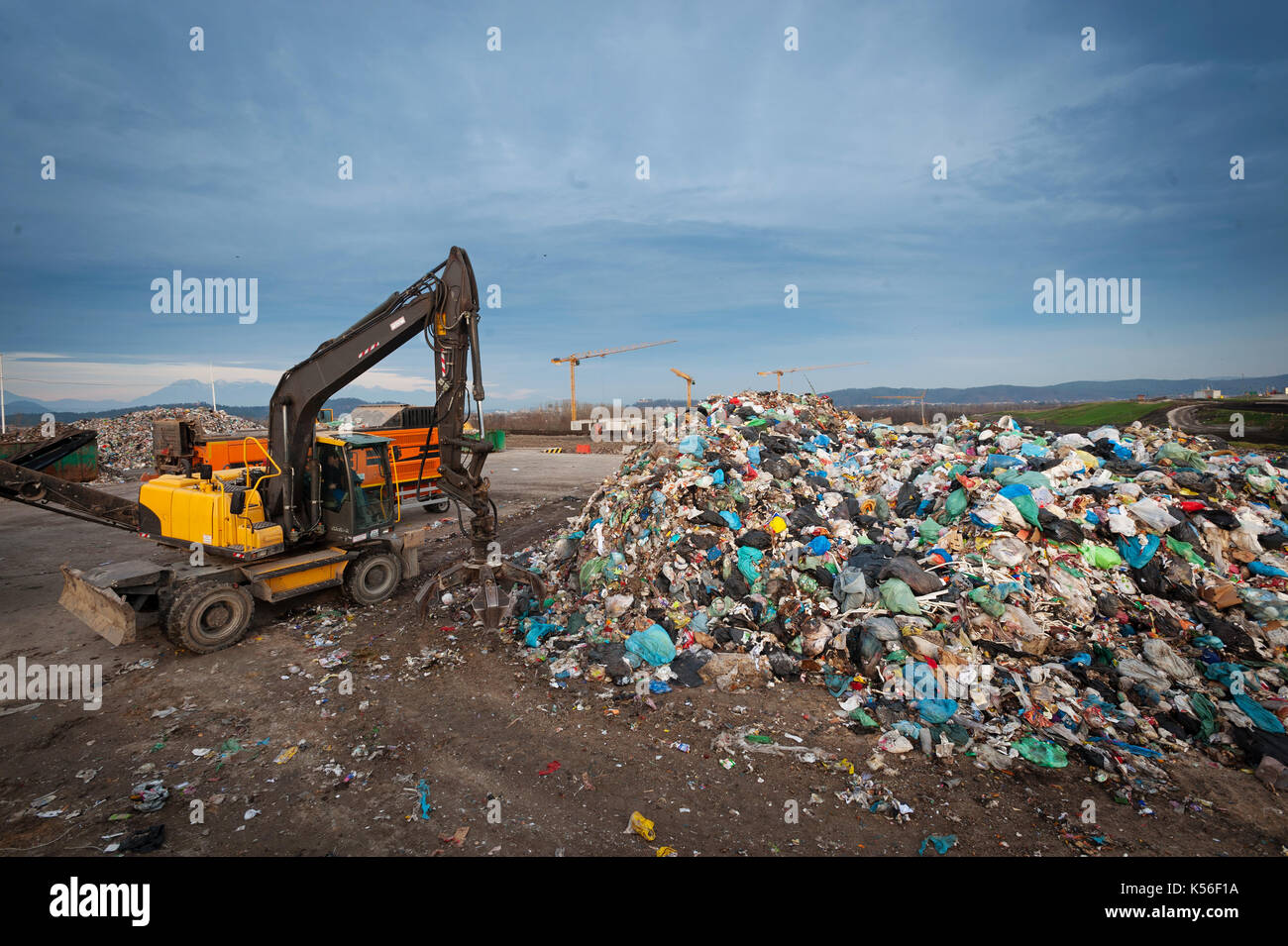 Bulldozer con braccio meccanico afferra i rifiuti provenienti da un palo a città discarica. La gestione dei rifiuti, il concetto di ecologia. Foto Stock