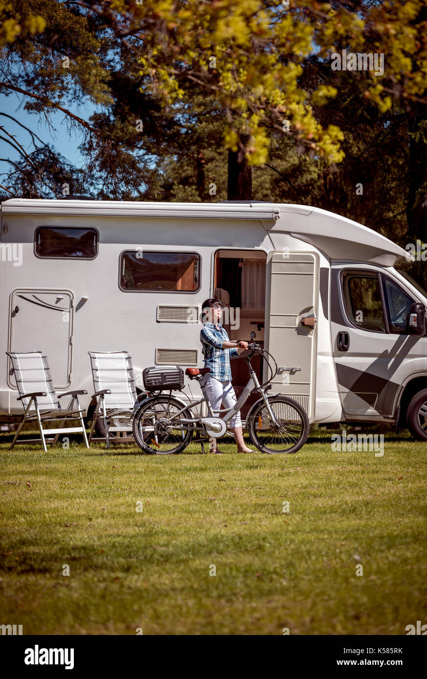 Donna sulla bicicletta elettrica in appoggio al campeggio. vacanza con la famiglia in viaggio, viaggio vacanza in camper, caravan auto vacanza. Foto Stock
