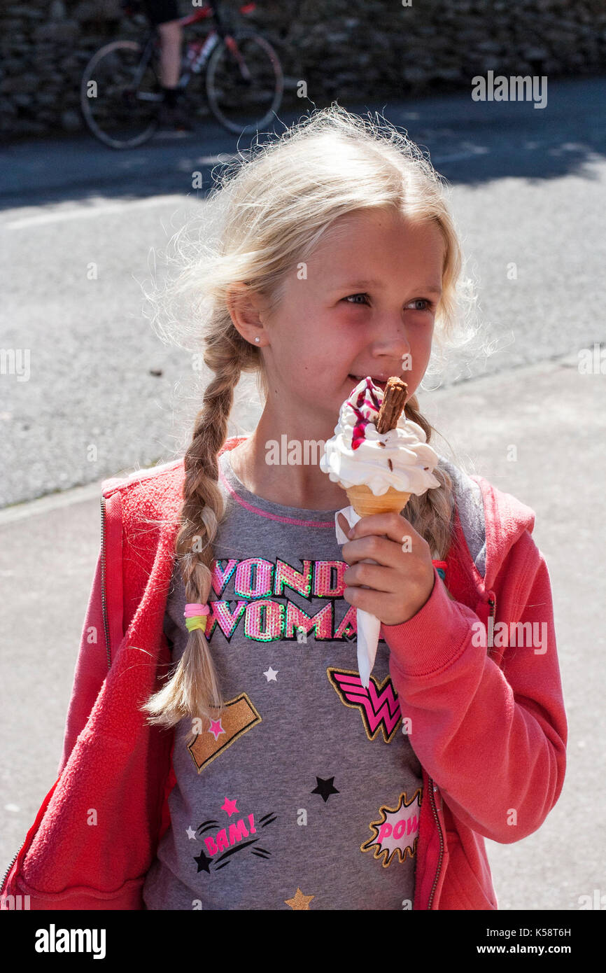 Ragazza a mangiare il gelato cono con scaglie di cioccolato in esso in una calda giornata estiva, vita migliore concetto, la felicità, la gioia concetto, Bliss, 99, giornata di sole Foto Stock