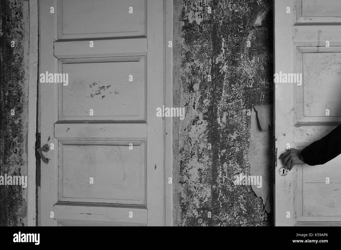 Braccio con la bambola mano sulla porta di un Haunted House. in bianco e nero. Foto Stock