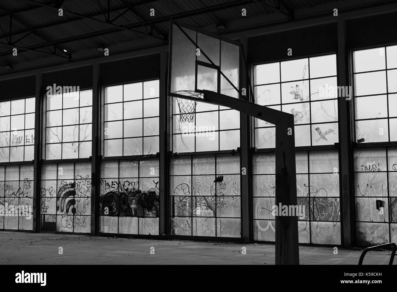 Abbandonato da pallacanestro palestra interna e parete in vetro finestre rotte. in bianco e nero. Foto Stock