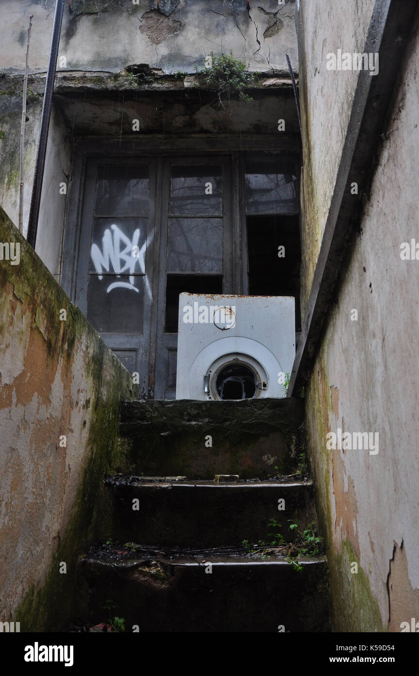 Casa abbandonata seminterrato scale e rotture di macchina di lavaggio sul giorno di pioggia. Foto Stock