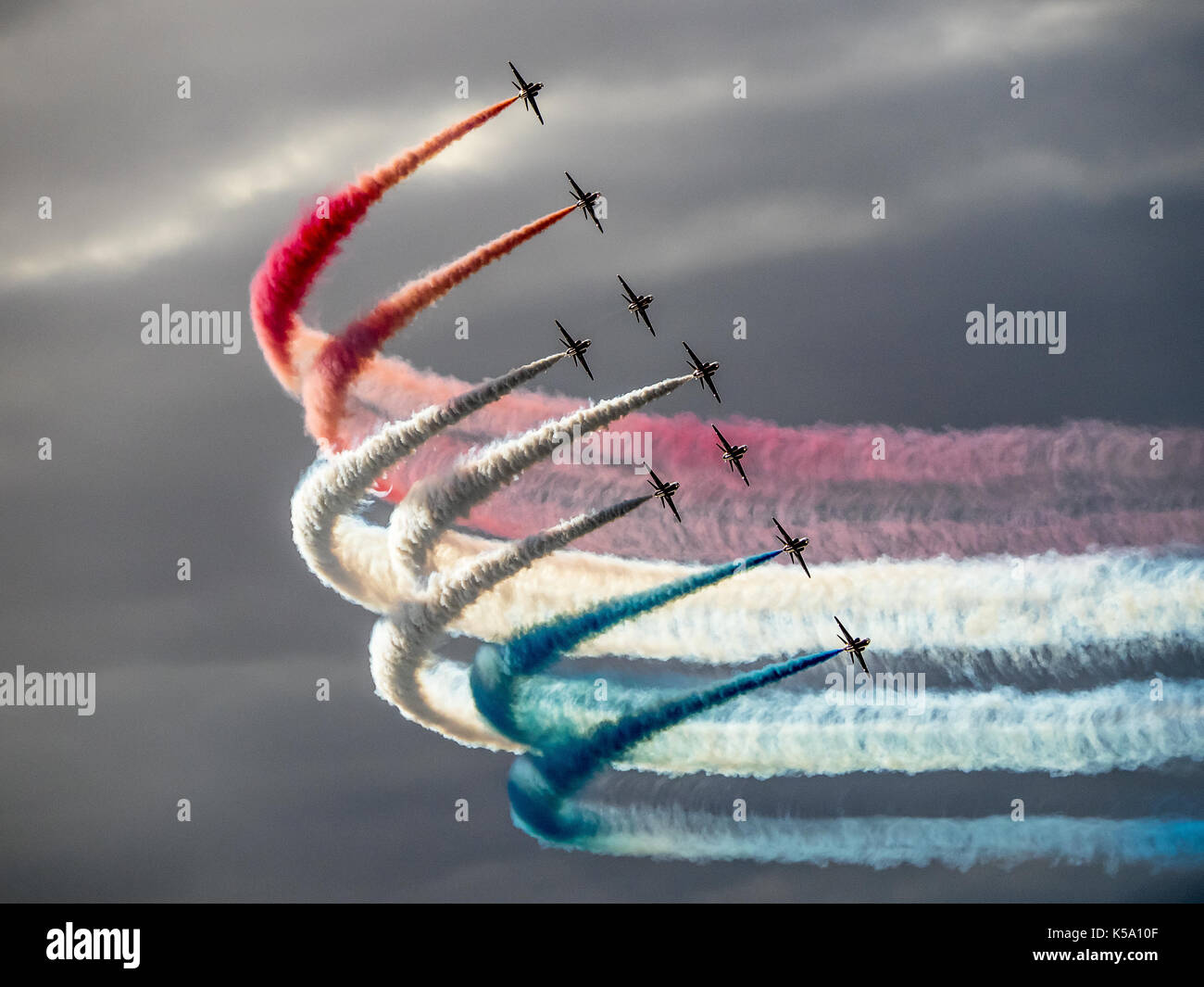 Le frecce rosse contro un cielo drammatico con fumo colorato sentieri Foto Stock