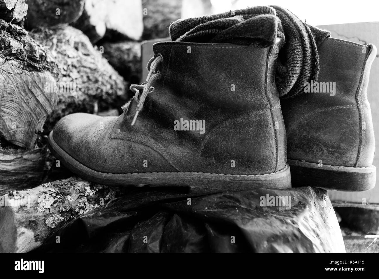 Stanco farmer's stivali sulla legna da ardere in bianco e nero Foto Stock