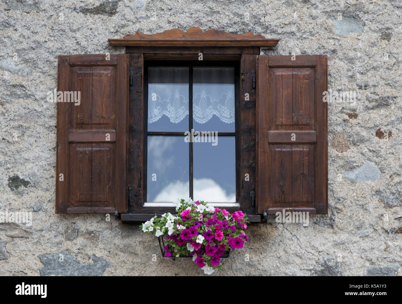 Finestra aperta con persiane di legno e fiori, Livigno, Italia Foto Stock
