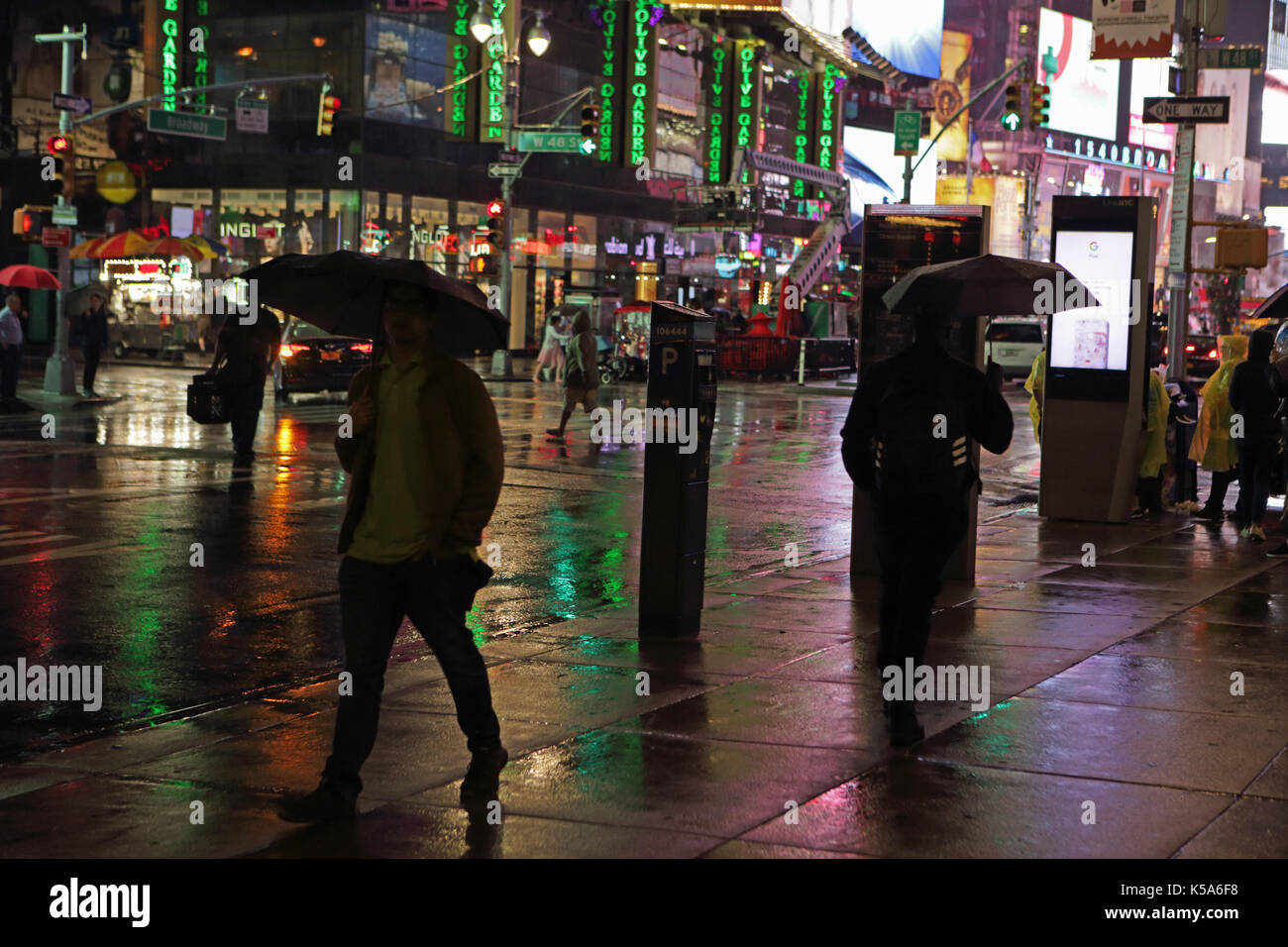 Notte piovosa in times square, i turisti con ombrelloni a piedi 7th Avenue e Broadway illuminata da billboard elettrico schermi pubblicitari Foto Stock