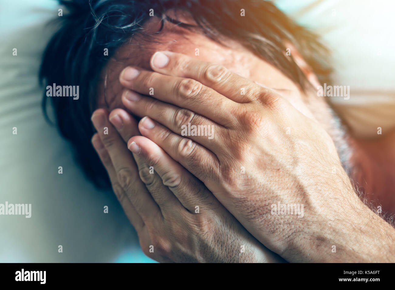 La depressione di mattina e come crisi di mezza età di un uomo nella sua 40s giacente in letto in mattinata con sintomi come estrema tristezza, di frustrazione e di rabbia e di fatica. Foto Stock