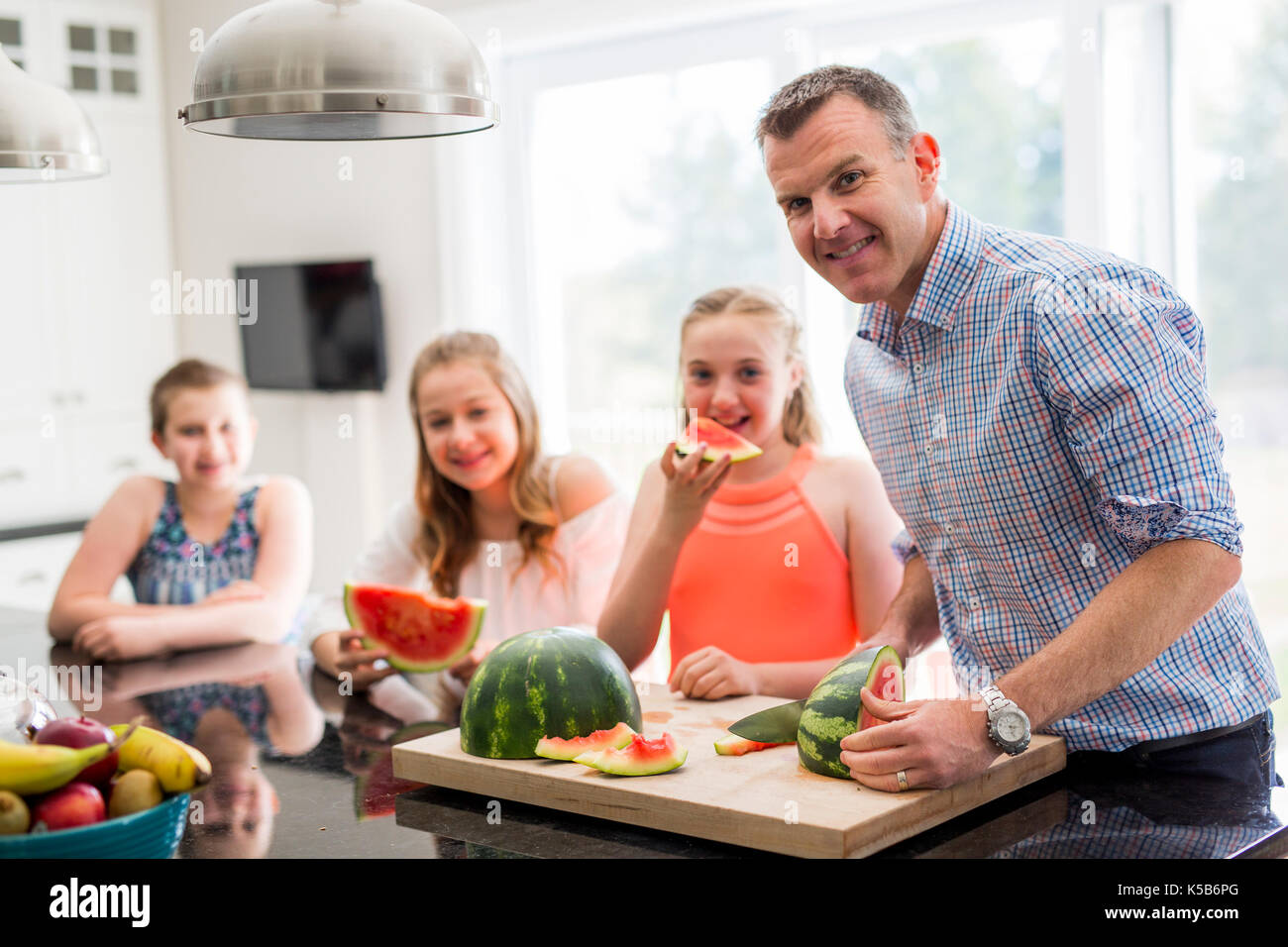 Famiglia in cucina cuting il cocomero Foto Stock