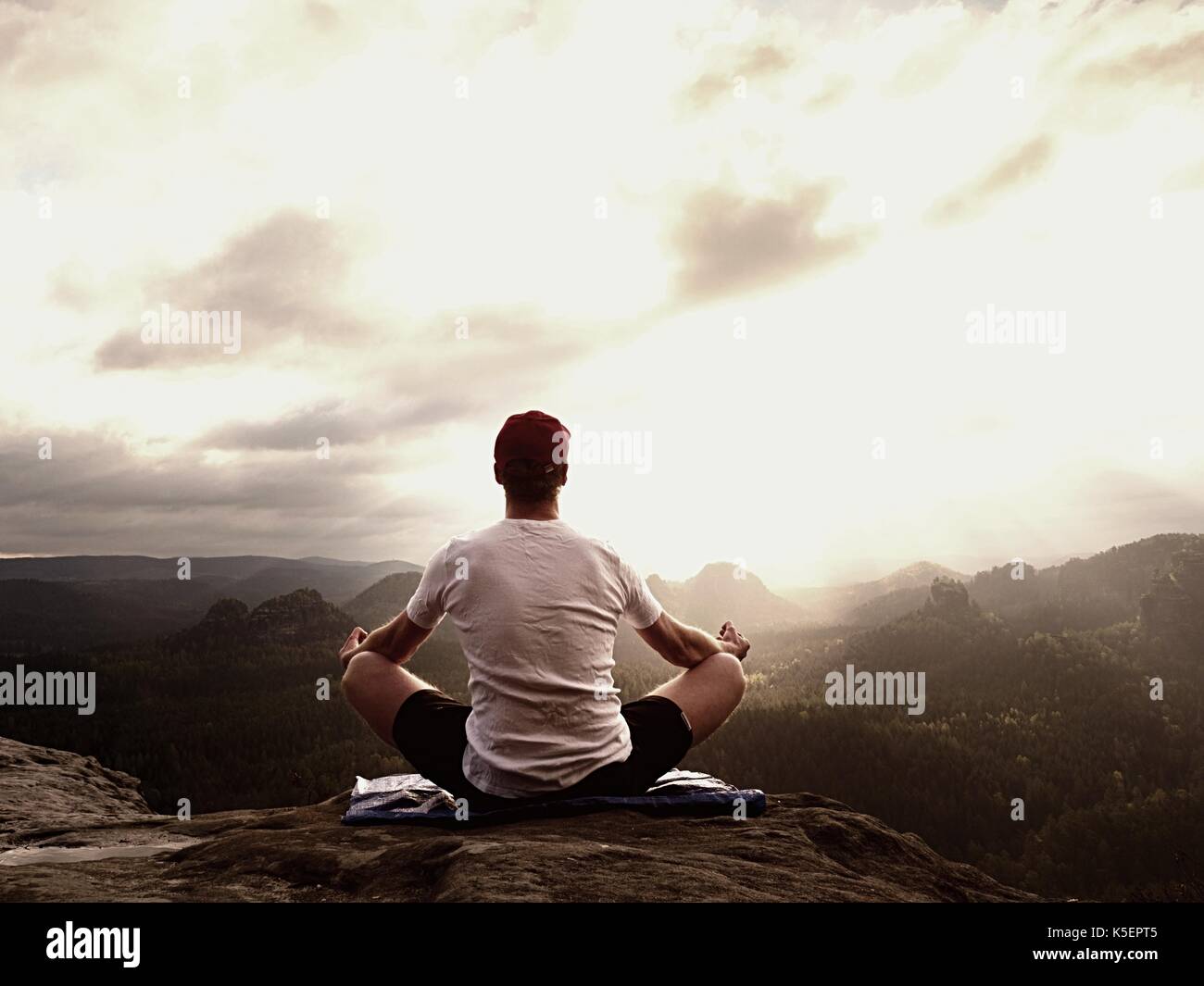 La pratica dello yoga al vertice di montagna con vista aerea della valle di montagna. alto atleta a praticare yoga e meditazione in montagna durante il lusso Foto Stock