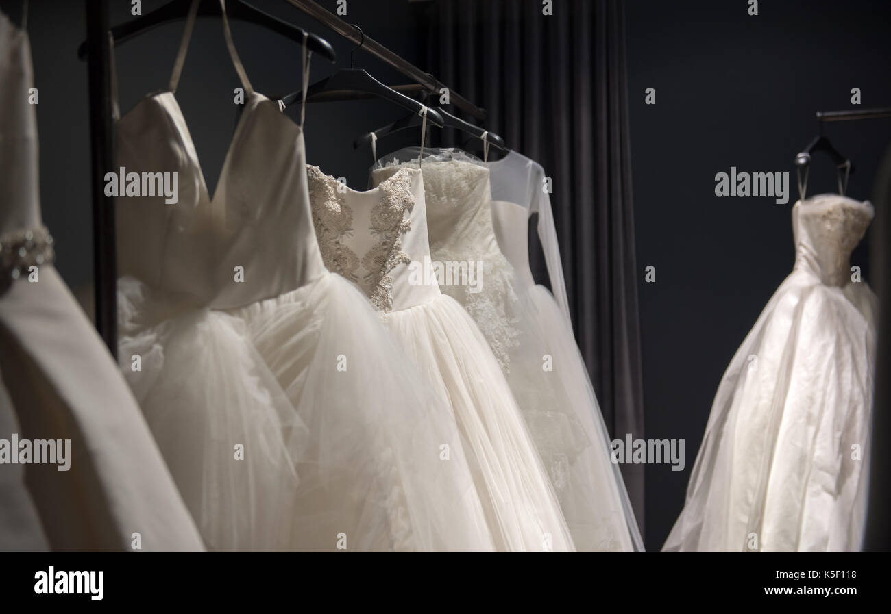 Selezione di bianco abiti da sposa o abiti a sfera sul display appeso su rotaie con il fuoco selettivo per una illuminata da evidenziare Foto Stock