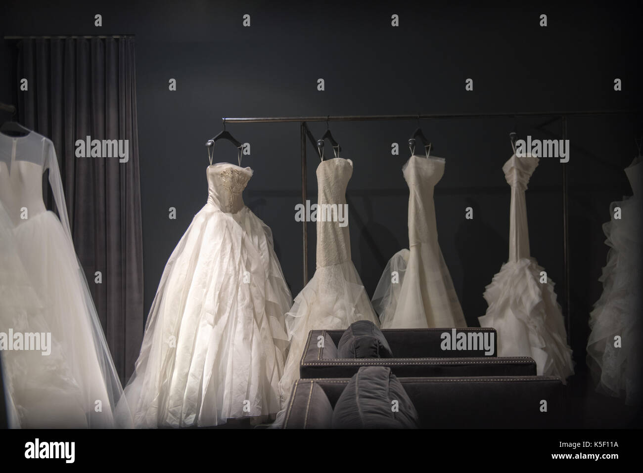 Selezione di bianco abiti da sposa o abiti a sfera sul display appeso su rotaie con il fuoco selettivo per una illuminata da evidenziare Foto Stock