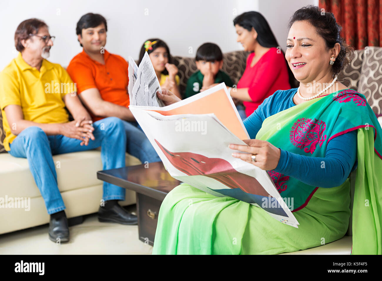 Famiglia indiana con i senior donna leggendo il giornale in primo piano a home Foto Stock