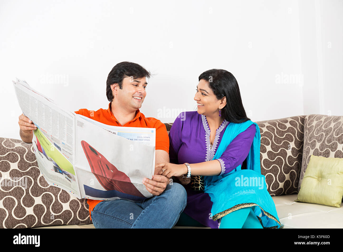 Adulto Giovane la condivisione di un quotidiano a casa mentre siete seduti sul divano Foto Stock