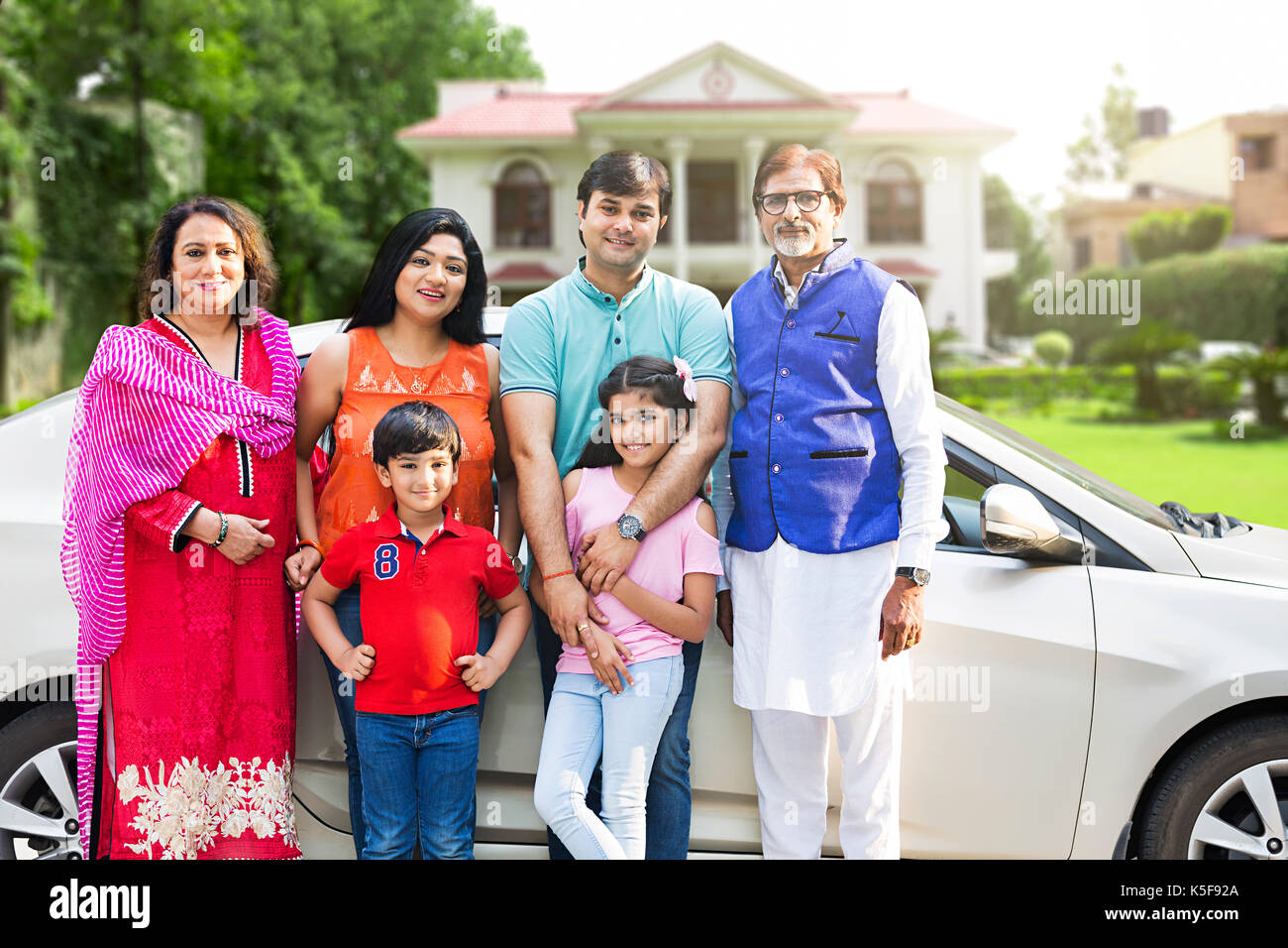 Felice indian grande famiglia in piedi da un cortile auto agriturismo l'acquisto di beni immobili Foto Stock
