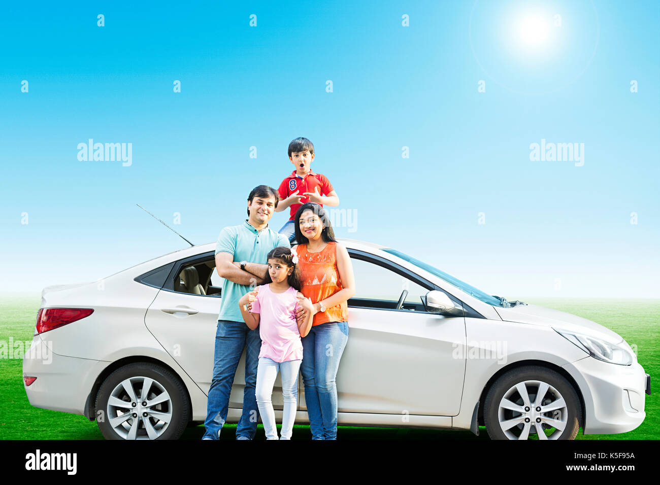 Felice famiglia indiana in piedi da un parcheggio auto viaggi vacanze weekend godetevi Foto Stock