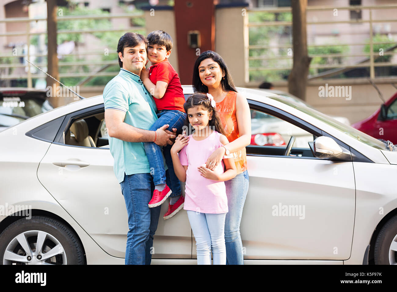 Famiglia i genitori e i bambini in piedi da un acquisto di auto nuove auto Foto Stock