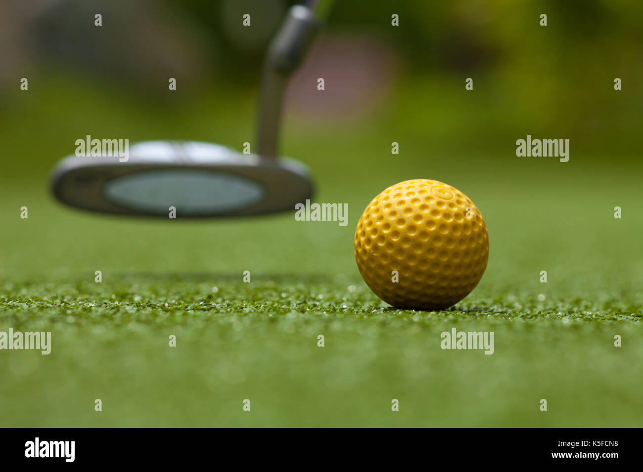Golf club e sfera gialla su erba artificiale Foto Stock