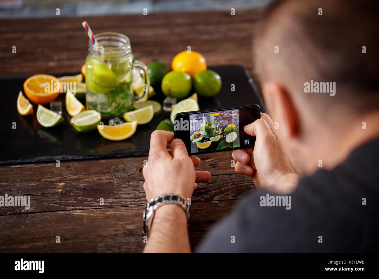 L'uomo prendendo foto sullo smartphone di bere mojito Foto Stock