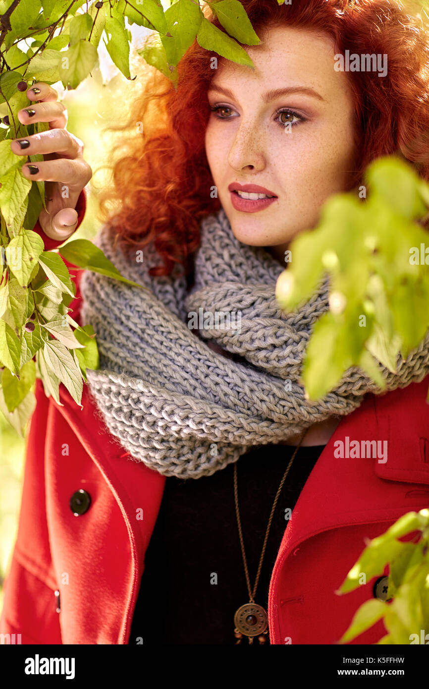 Curly capelli rossi femmina in natura tra gli alberi in autunno Foto Stock