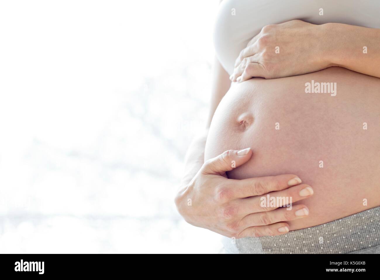 Donna incinta toccando la pancia. Foto Stock