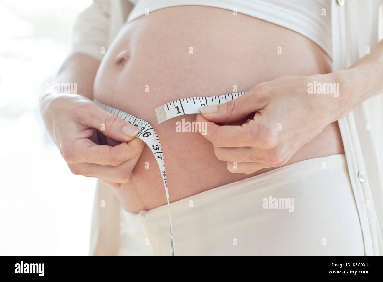 Donna incinta pancione di misurazione con nastro di misurazione. Foto Stock