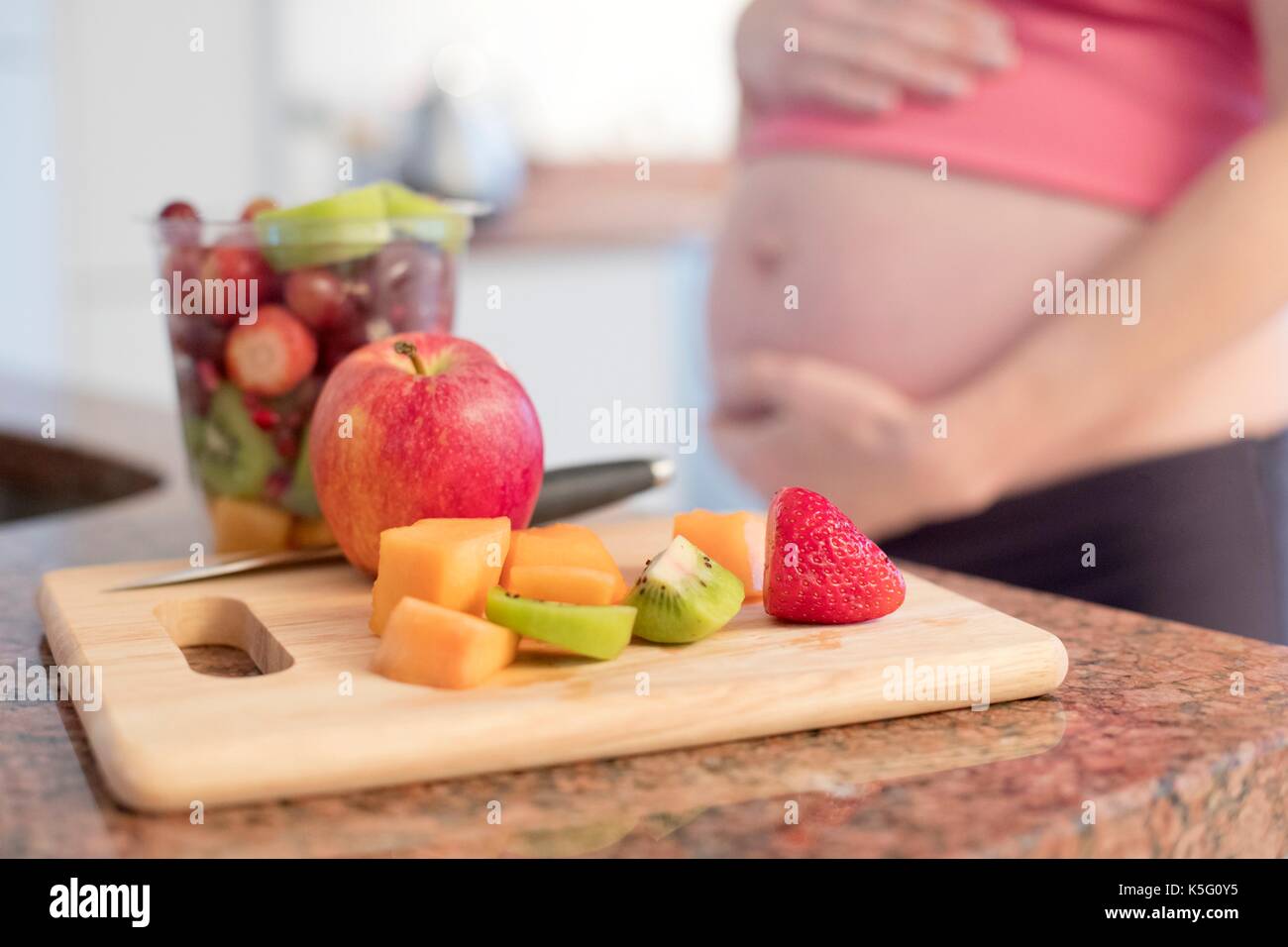 Appena tagliate la frutta a bordo con la donna incinta in background. Foto Stock