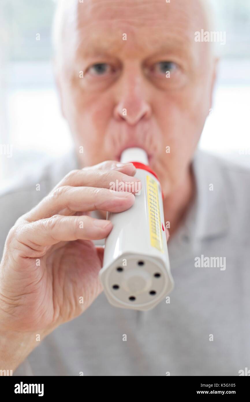 Senior uomo con misuratore del picco di flusso espiratorio. Foto Stock