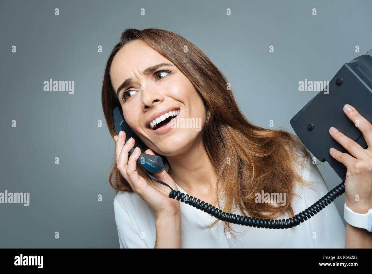 Bella donna emotiva in possesso di un ricevitore telefonico Foto Stock