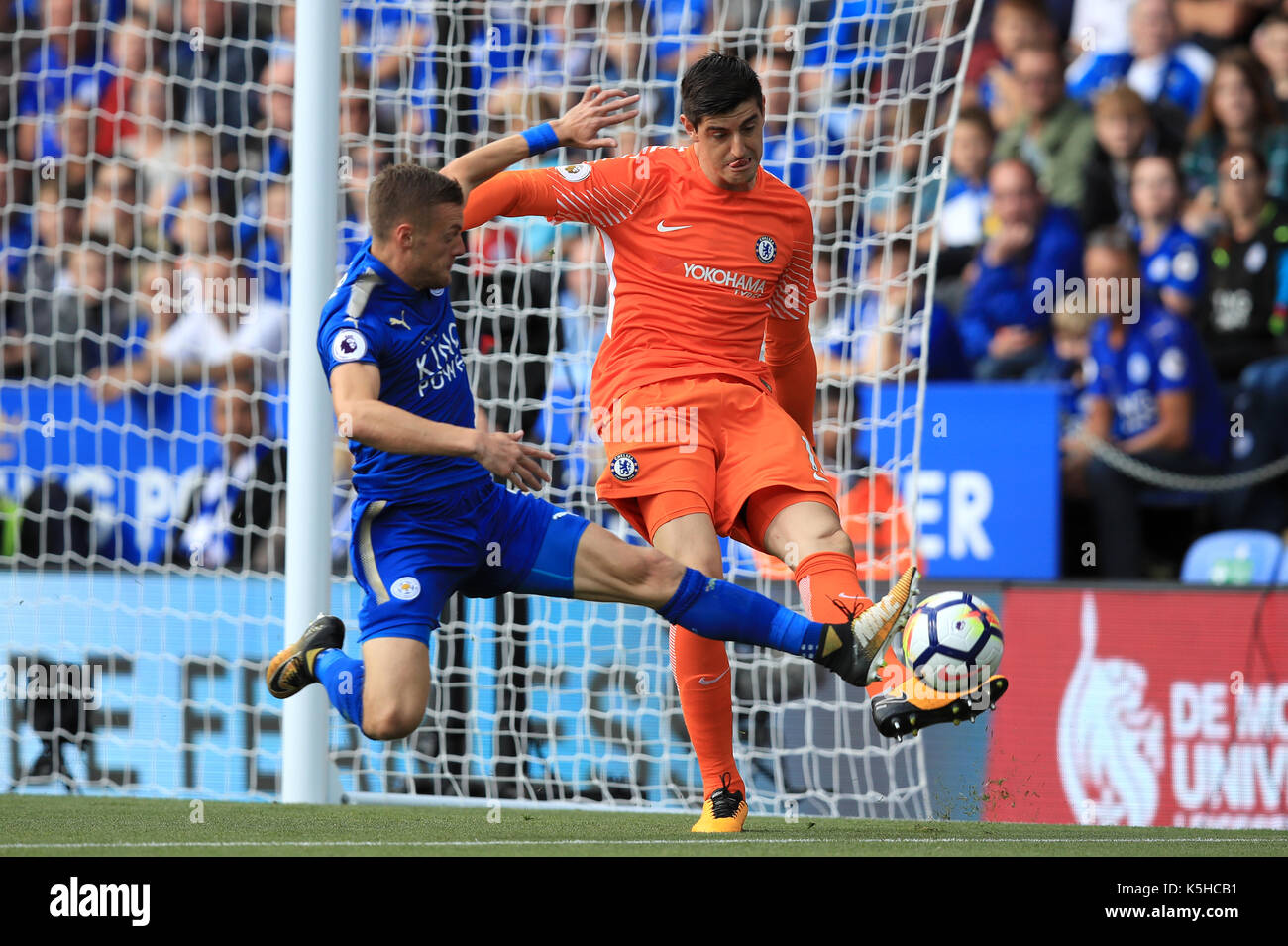 Chelsea portiere thibaut courtois (destra) cancella la palla sotto pressione da leicester city's jamie vardy durante il match di premier league al king power stadium, Leicester. Foto Stock