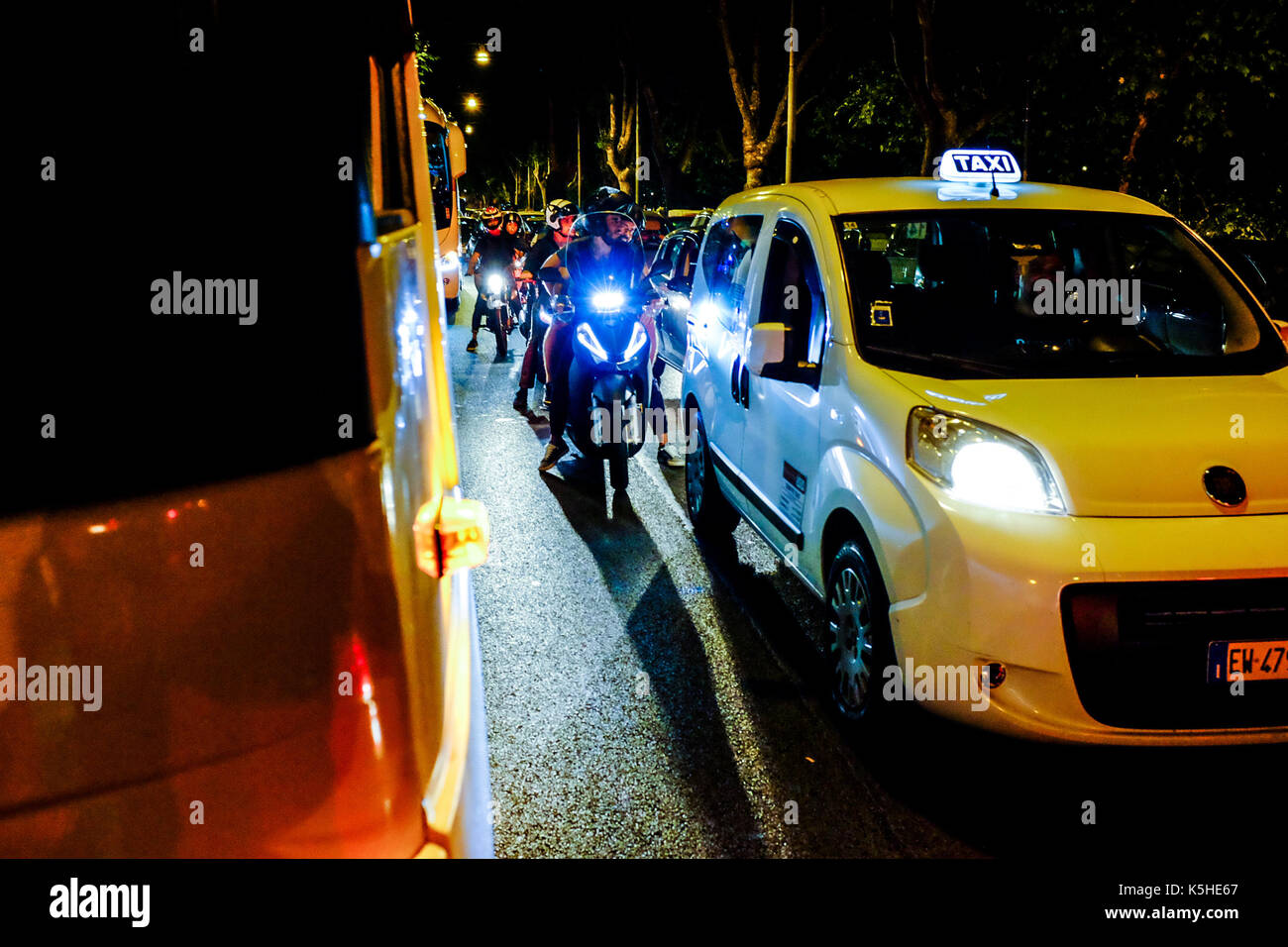 Gli autobus, automobili e motociclette e scooters lotta per lo spazio durante il traffico di notte ad Atene, Roma il 23 settembre 2017. Foto Stock