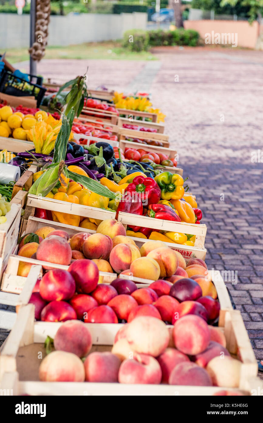 Pressione di stallo di mercato piena di colorati frutti e verdure mediterranee, pesche, peperone, melanzana Foto Stock