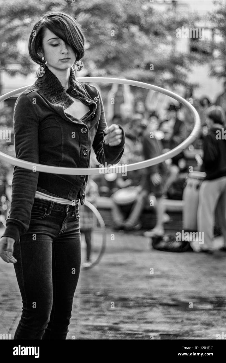 Una ragazza adolescente hula hoops, da soli in una folla, in corrispondenza del tamburo cerchio a Pritchard Park nel centro cittadino di Asheville, NC, Stati Uniti d'America Foto Stock