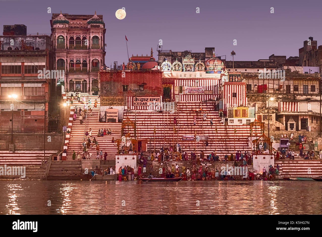 Una folla di persone la balneazione nel fiume Gange prima che il Sole arriva fino al giorno dopo dev diwali. la luna è in 'super luna' di fase. Foto Stock