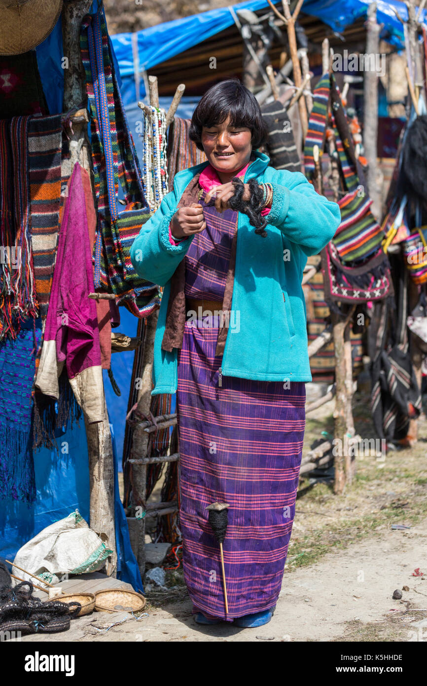 Signora la filatura yak capelli mentre tendendo artigianato e souvenir si erge a pele la mountain pass, centrale bhutan Foto Stock